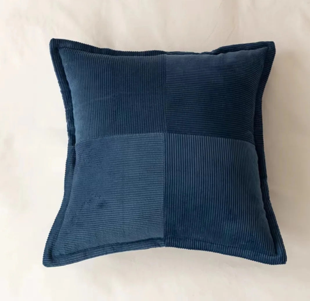 Un coussin en velours côtelé bleu marine avec un motif de lignes verticales formant un design élégant et graphique.