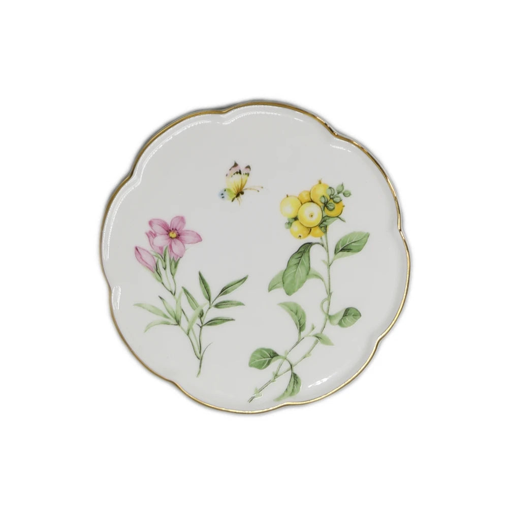 Une assiette décorative en porcelaine blanche ornée de fleurs et de feuillage colorés.