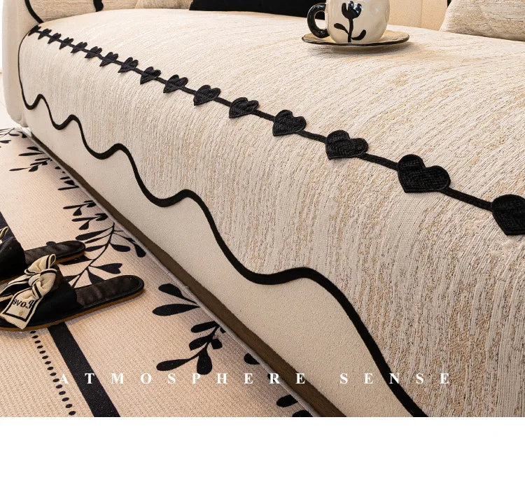 Cette image montre un gros plan d'un canapé avec un motif floral noir et blanc, avec des coussins décoratifs et un élément en céramique sur une table basse.