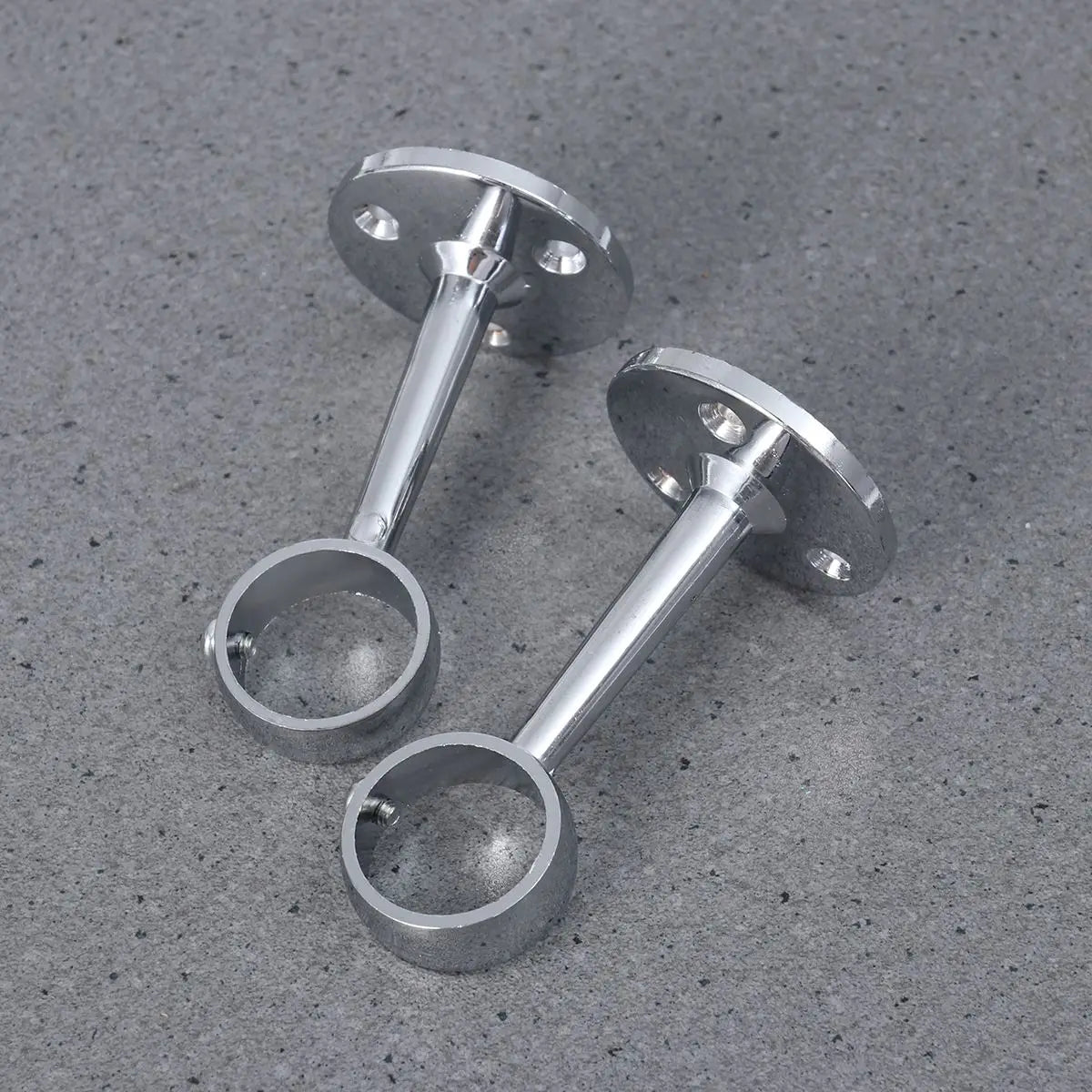 Vue de deux supports muraux chromés placés à l’horizontale sur fond gris, avec vis de fixation visibles.