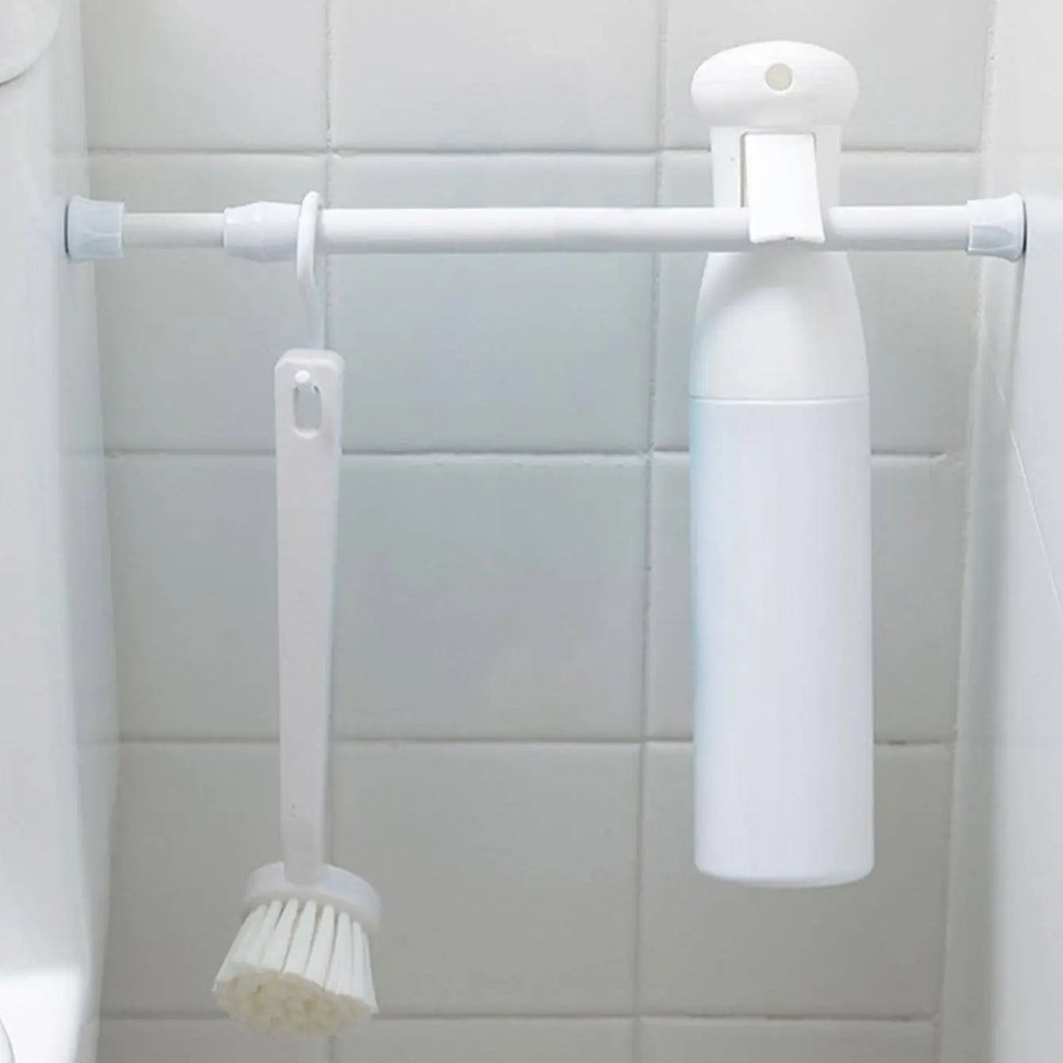 Tringle à rideaux blanche sans perçage utilisée dans une salle de bain pour suspendre une brosse et un vaporisateur.