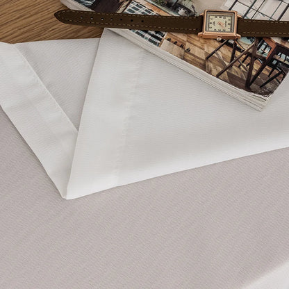 Zoom sur les finitions couture d’un voilage blanc, avec une montre et un magazine en décoration.
