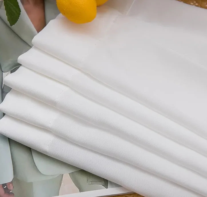 Tissu blanc de voilage à galon fronceur soigneusement plié sur une table, prêt à être posé sur rail