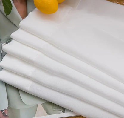 Tissu blanc de voilage à galon fronceur soigneusement plié sur une table, prêt à être posé sur rail