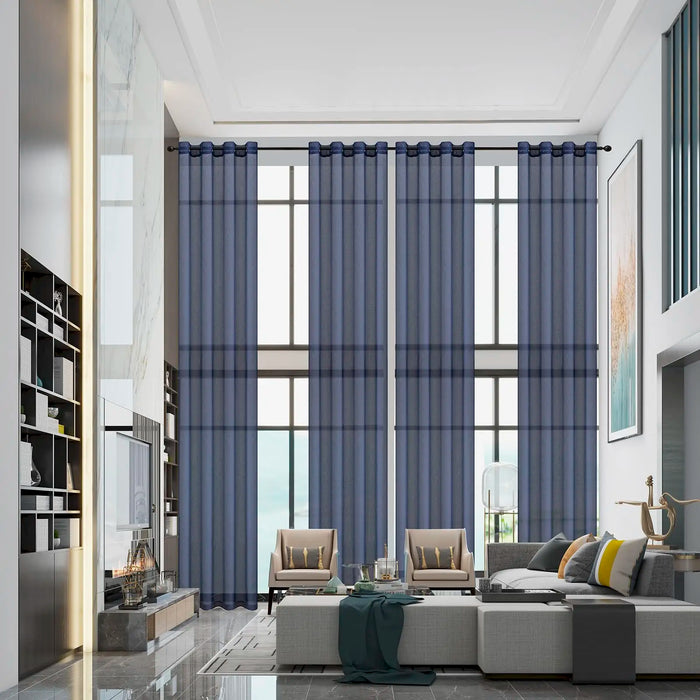 Voilage bleu marine suspendu dans un salon moderne avec plafond haut et grandes baies vitrées, créant une ambiance élégante et lumineuse.