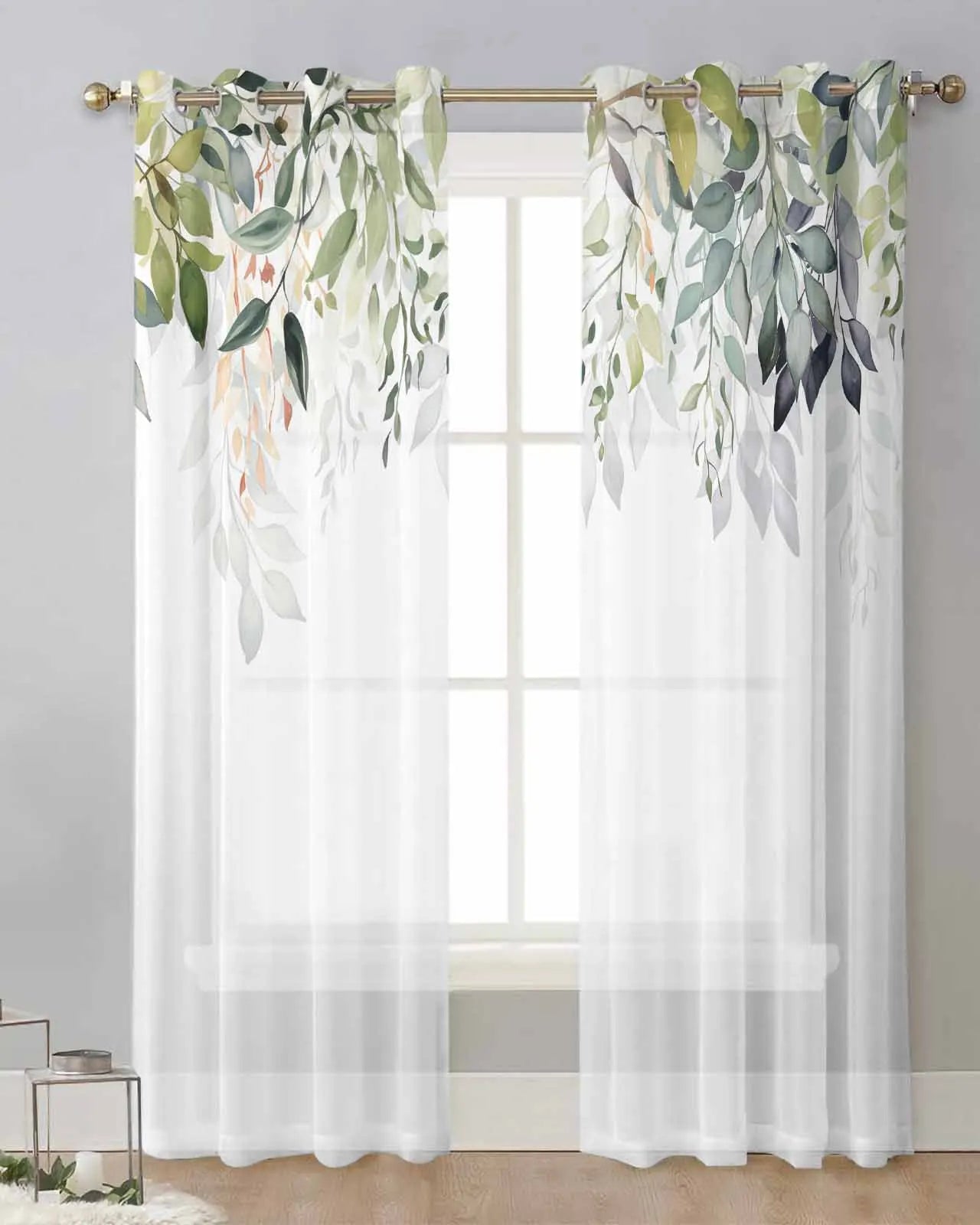 Rideau voilage blanc décoré de feuillages suspendu à une tringle dorée devant une fenêtre avec mur blanc et sol en bois clair.