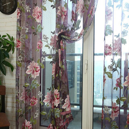 Voilage transparent à motif floral rose et violet noué élégamment sur une porte-fenêtre.