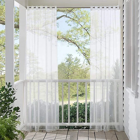 Voilages transparents blancs suspendus sur une terrasse couverte, laissant filtrer la lumière tout en préservant l’intimité.