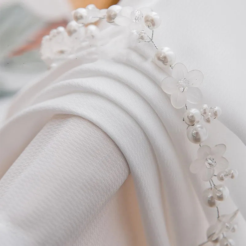 Gros plan sur le tissu du voilage blanc montrant la finesse de la maille avec une décoration florale perlée