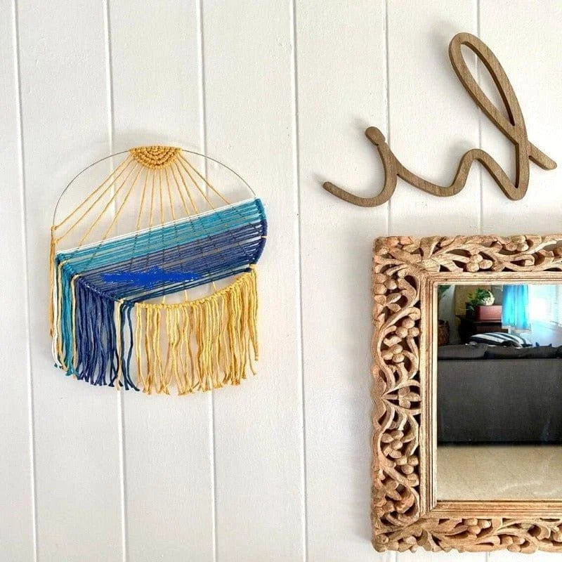 Décoration murale colorée avec des tons bleus et jaunes, parfaite pour ajouter une touche bohème à votre intérieur. Design captivant suspendu à côté d'un miroir sculpté et d'un élément décoratif en bois. Idéal pour embellir un salon ou une chambre.
