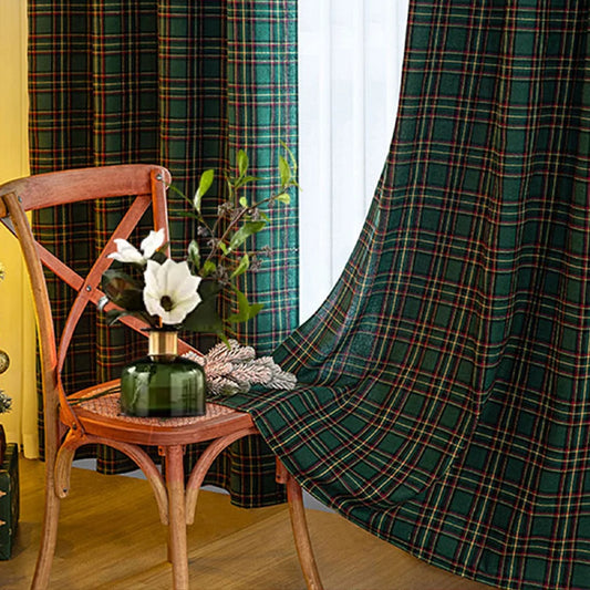 Rideau vert à carreaux dans une pièce chaleureuse, accompagné d’une chaise en bois avec un vase de fleurs blanches et feuillage vert.