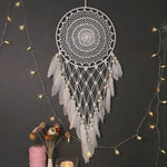 Capteur de rêves élégant avec plumes décoratives blanches, idéal pour une décoration murale bohème. Parfait pour créer une ambiance apaisante dans une chambre ou un salon. Associations harmonieuses avec des guirlandes lumineuses et décorations florales. Idéal pour ajouter une touche de sérénité et de mystère à votre intérieur.