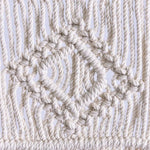 Détail d'une création en macramé avec un motif géométrique, idéal pour ajouter une touche d'artisanat à votre décoration intérieure. Design élégant mettant en valeur des noeuds complexes pour un style bohème.