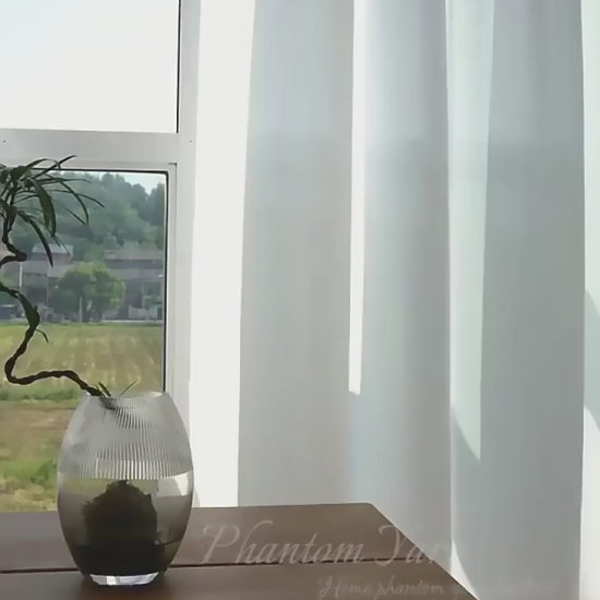 Vidéo d’un voilage blanc élégant flottant doucement dans la brise, laissant entrer une lumière douce dans une pièce au style épuré