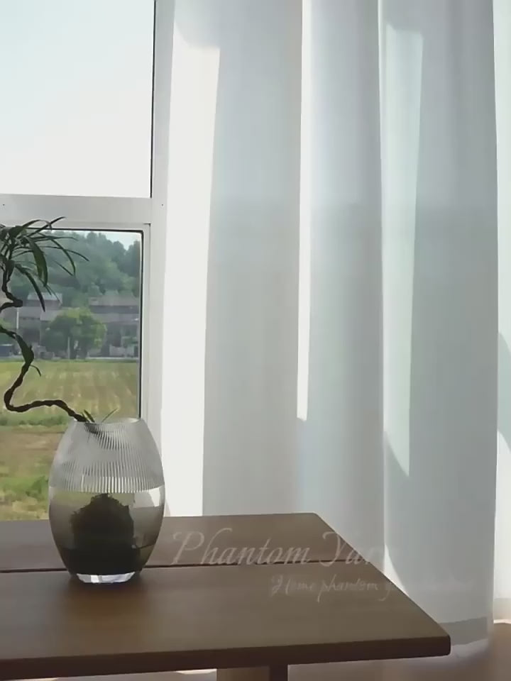 Vidéo d’un voilage blanc élégant flottant doucement dans la brise, laissant entrer une lumière douce dans une pièce au style épuré