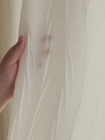 Zoom sur un voilage blanc froissé avec une main en transparence pour illustrer la légèreté et la finesse du tissu.
