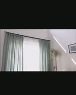 Présentation en mouvement d’un voilage en tulle gris, flottant à la lumière naturelle et illustrant sa légèreté et sa transparence.
