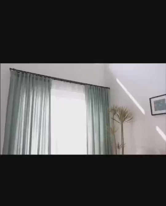 Présentation en mouvement d’un voilage en tulle gris, flottant à la lumière naturelle et illustrant sa légèreté et sa transparence.