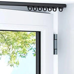 Rail de rideau noir, fixé au-dessus d'une porte-fenêtre moderne. Système de suspension avec anneaux, idéal pour une installation élégante et discrète. Permet un glissement fluide des rideaux, parfait pour optimiser l'espace intérieur tout en ajoutant une touche contemporaine à votre décoration.