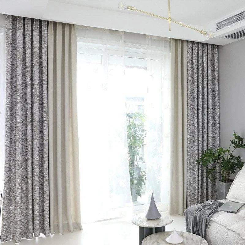 Vue d’ensemble d’un salon lumineux avec double-rideaux américains à motifs végétaux et voilage léger, ambiance épurée.