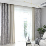 Vue d’ensemble d’un salon lumineux avec double-rideaux américains à motifs végétaux et voilage léger, ambiance épurée.