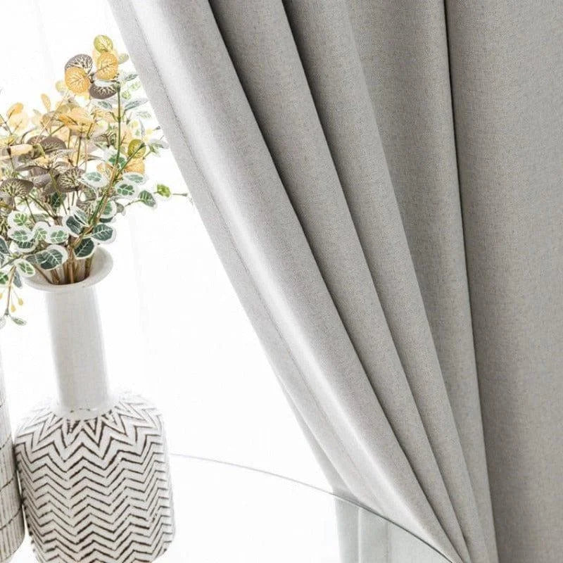Rideau élégant de couleur grise, idéal pour sublimer votre décoration d'intérieur moderne. Parfait pour ajouter une touche de sophistication à votre salon ou chambre à coucher. Accompagné d'un vase décoratif avec des plantes artificielles pour un style raffiné et contemporain.