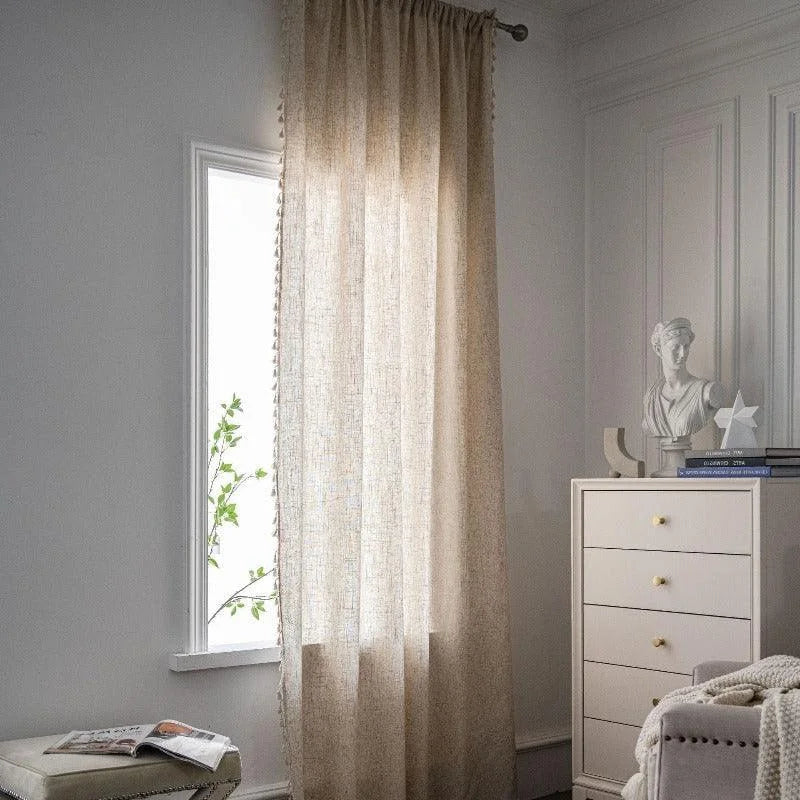 Rideau beige élégant dans un intérieur moderne et lumineux, habillant une fenêtre pour apporter une touche de sophistication à la pièce. Commode blanche avec décoration minimaliste et sculpture classique offrant un cadre raffiné et apaisant. Idéal pour ajouter une ambiance chaleureuse à une chambre à coucher ou un salon.