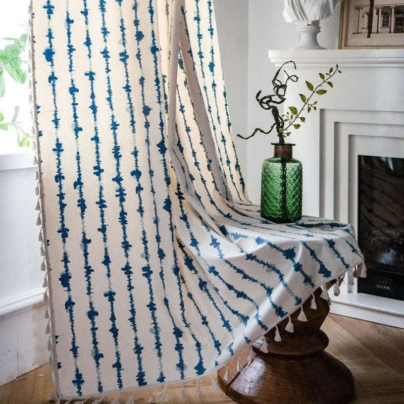 Voilage élégant à motifs bleus, parfait pour ajouter une touche de style à votre intérieur. Ce rideau décoratif avec des motifs alignés verticalement crée une ambiance moderne et raffinée, idéal pour le salon ou la chambre. Agrémenté d'un vase vert et d'une décoration végétale, il complète parfaitement un décor contemporain et épuré près de la cheminée.