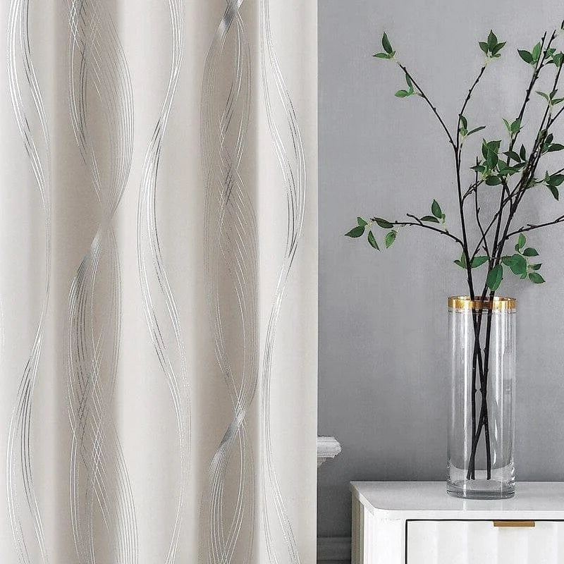 Rideau décoratif moderne avec motif ondulé argenté, idéal pour un salon élégant. Le rideau est présenté à côté d'un vase cylindrique transparent avec des branches de feuillage, ajoutant une touche zen et naturelle à l'intérieur. Parfait pour créer une atmosphère apaisante et sophistiquée dans votre espace de vie.