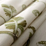 Tissu décoratif beige aux motifs brodés verts, idéal pour la confection de rideaux ou d'ameublement intérieur. Design élégant inspiré de la nature, parfait pour ajouter une touche de fraîcheur à votre décoration intérieure. Finition soignée et motifs végétaux subtils pour un style moderne et raffiné.