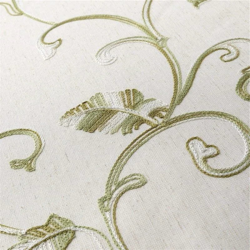 Image d'un tissu raffiné avec des motifs brodés en forme de feuilles et de volutes dans des teintes vertes et blanches, idéal pour la décoration intérieure élégante. Design floral délicat et détaillé, parfait pour ajouter une touche naturelle et sophistiquée à votre espace de vie.