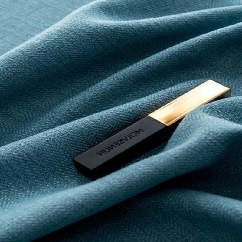 Gros plan sur un produit rectangulaire noir et doré posé sur un tissu bleu, mettant en valeur le contraste élégant et sophistiqué du design.
