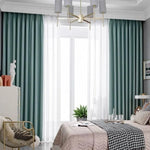 Chambre moderne avec rideaux vert émeraude et voilages blancs, offrant une ambiance élégante et apaisante. Le design du luminaire et les décorations contemporaines complètent la décoration raffinée de la pièce. Cette chambre bien aménagée crée un espace confortable et accueillant.