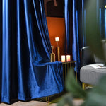 Rideaux élégants bleu nuit créant une ambiance sophistiquée dans un salon moderne. Décoration intérieure raffinée avec bougies et mobilier contemporain. Idéal pour ajouter une touche de luxe et de confort à votre espace de vie.