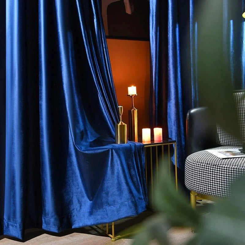 Rideaux élégants bleu nuit créant une ambiance sophistiquée dans un salon moderne. Décoration intérieure raffinée avec bougies et mobilier contemporain. Idéal pour ajouter une touche de luxe et de confort à votre espace de vie.