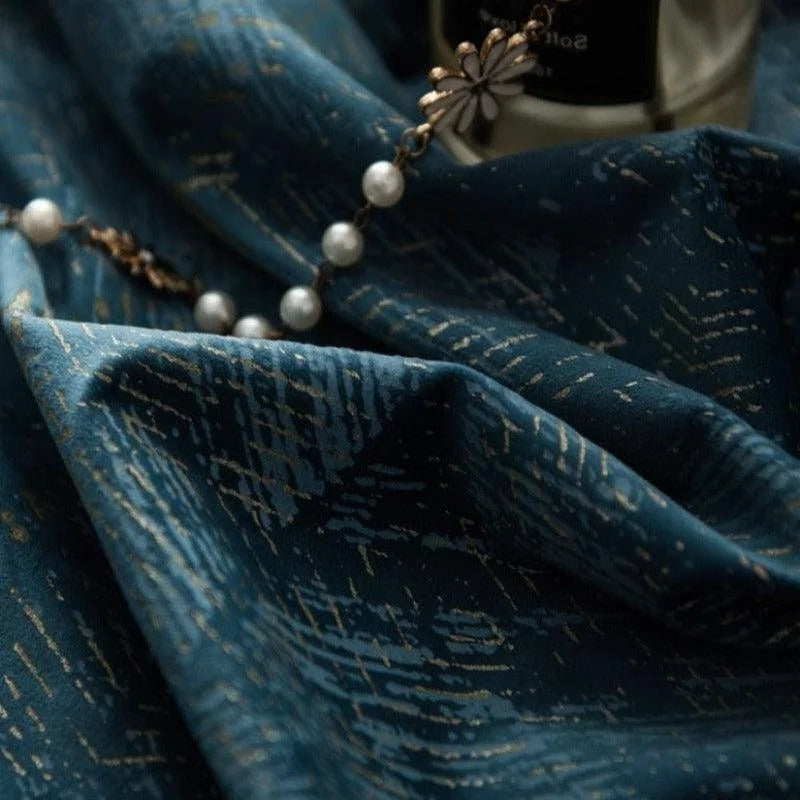 Drapé élégant de couleur bleue avec motif doré subtil, accompagné d'un bracelet délicat avec perles blanches et décoration florale. Parfait pour ajouter une touche de luxe et de sophistication à votre décoration intérieure ou tenue. Ambiance chic et raffinée idéale pour les occasions spéciales.