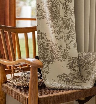 Rideau élégant à motifs floraux sur chaise en bois tressé, créant une ambiance chaleureuse et naturelle dans une maison lumineuse. Parfait pour ajouter une touche de style à votre intérieur tout en préservant l'intimité lumineuse.