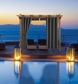 Pergola élégante avec rideaux opaques gris sur terrasse en bord de mer, offrant une ambiance relaxante au coucher du soleil. Parfait pour créer un espace extérieur privé et protégé du soleil. Idéal pour les jardins, terrasses ou espaces de détente en extérieur. Accessoire chic et fonctionnel pour vos moments de détente en plein air.
