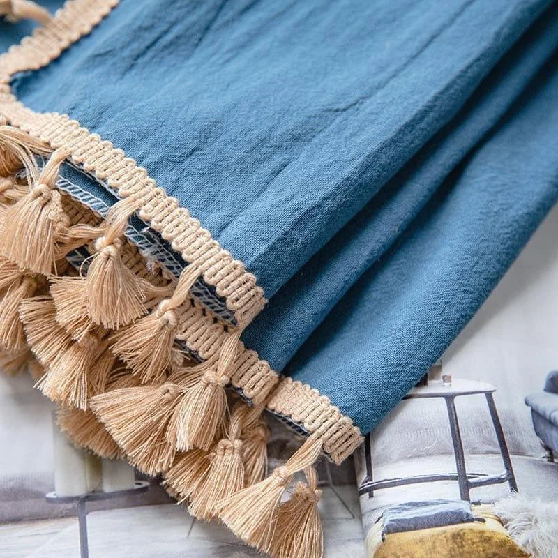 Une couverture élégante de couleur bleue ornée de franges décoratives beiges. Cette pièce ajoute une touche de style et de chaleur à tout intérieur, idéale pour le salon ou la chambre à coucher. Une couverture parfaite pour se blottir et embellir votre espace de vie.