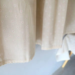Tissu beige à motif délicat de petites fleurs blanches et rouges, avec bordure en dentelle. Design élégant et raffiné, idéal pour la confection de vêtements féminins ou de décorations d'intérieur. Parfait pour apporter une touche douce et romantique à votre projet textile.
