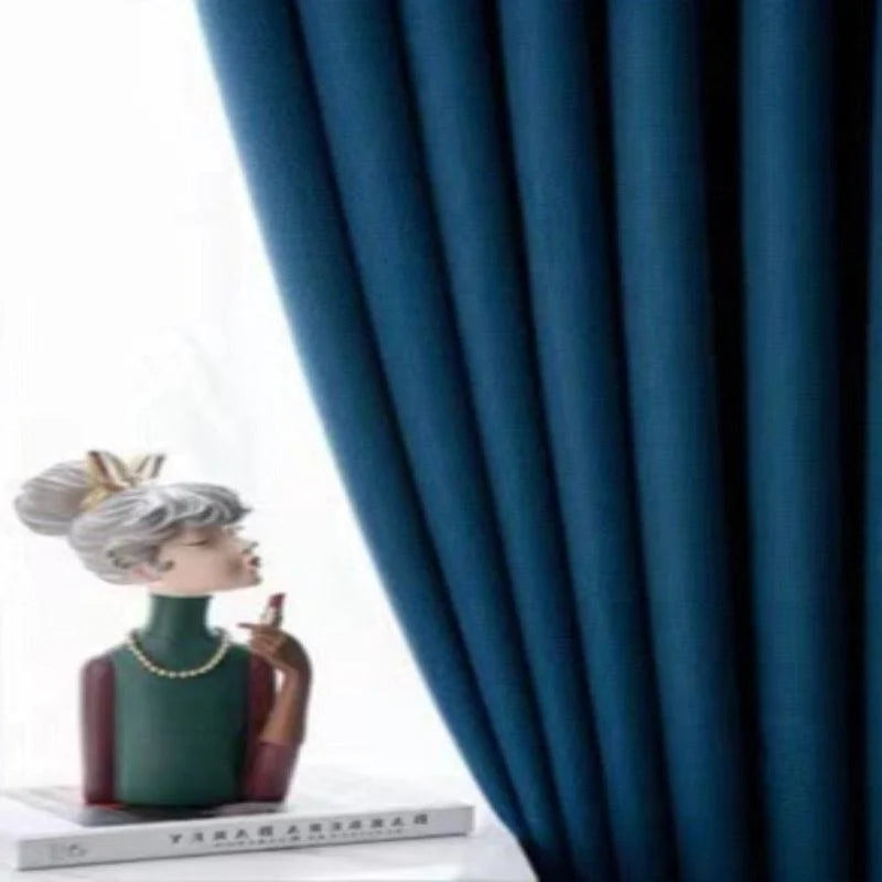 Rideau bleu élégant dans un intérieur moderne avec décoration de figurine artistique. Parfait pour ajouter une touche de sophistication et de style à votre salon ou chambre. Créez une ambiance chaleureuse avec ce design contemporain et raffiné.