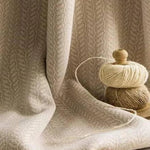 Tissu beige texturé avec pelotes de fil beige et marron posées à côté. Idéal pour la décoration intérieure ou des projets de couture. Élégant et sobre, ce tissu s'intégrera parfaitement dans un environnement moderne ou traditionnel grâce à son motif discret et raffiné. Parfait pour concevoir des rideaux ou des nappes qui ajoutent une touche de chaleur à votre espace.