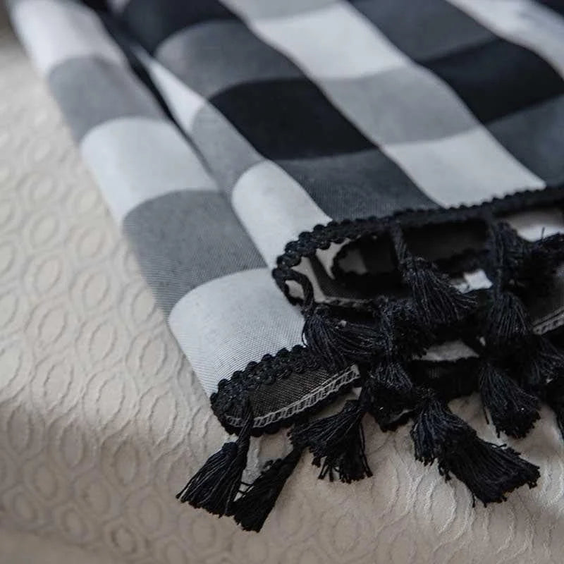 Écharpe élégante à motifs carreaux noir et blanc avec franges, parfaite pour un style moderne et sophistiqué. Accessoire idéal pour ajouter une touche chic à toute tenue.