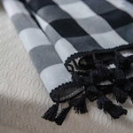 Écharpe élégante à motifs carreaux noir et blanc avec franges, parfaite pour un style moderne et sophistiqué. Accessoire idéal pour ajouter une touche chic à toute tenue.