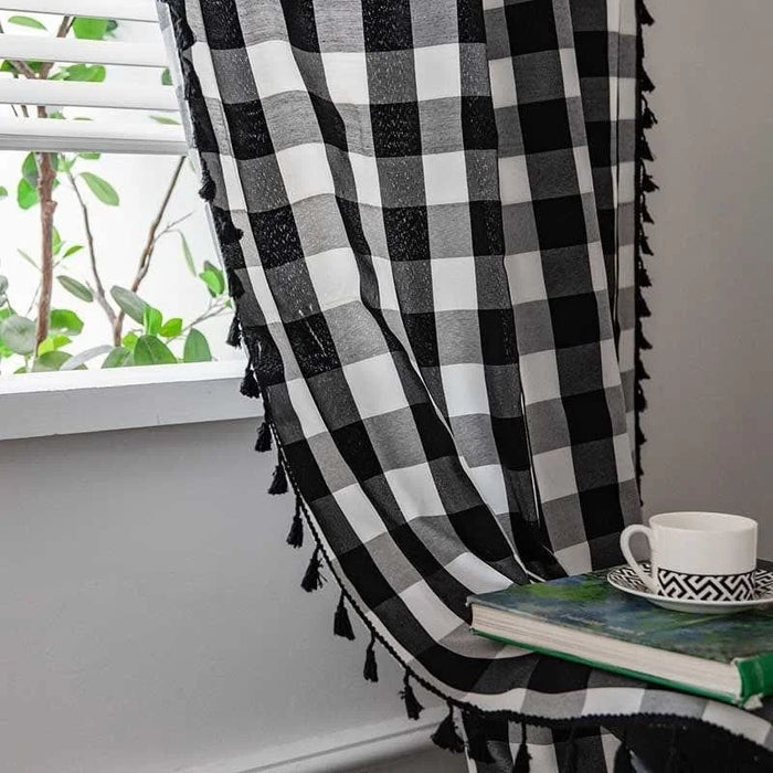 Tissu à carreaux noir et blanc avec franges, idéal pour la décoration intérieure, suspendu près d'une fenêtre. Accessoire élégant pour habiller vos fenêtres.