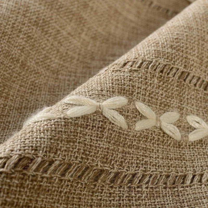 Gros plan sur un tissu élégant avec une délicate broderie florale, idéal pour une décoration intérieure chic et naturelle. Conçu pour ajouter une touche artisanale à tout espace de vie, ce tissu raffiné offre une esthétique sobre et intemporelle. Parfait pour les amateurs de design raffiné cherchant à optimiser le confort et la beauté de leur intérieur.