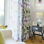 Rideaux élégants à motifs floraux colorés embellissant un salon moderne. Associés à un fauteuil confortable et une table d'appoint décorée, ces rideaux ajoutent une touche de fraîcheur et de style à votre intérieur. Parfaits pour une ambiance lumineuse et accueillante.