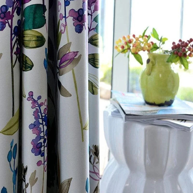 Rideau floral coloré suspendu devant une fenêtre, ajoutant une touche de fraîcheur printanière à la décoration intérieure. Le motif floral vibrant avec des nuances de violet, vert et bleu crée une ambiance accueillante et lumineuse. Parfait pour égayer un salon ou une chambre avec style et élégance. Idéal pour les espaces nécessitant un relooking avec une note naturelle et sophistiquée.