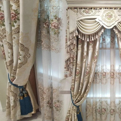 Rideaux élégants à motifs floraux avec embrasses décoratives bleues, éléments festonnés et détails en franges. Idéal pour embellir le salon ou la chambre, ce design raffiné apporte une touche de sophistication à votre intérieur.