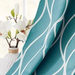 Rideau moderne bleu avec motif ondulé blanc, idéal pour une décoration intérieure élégante et contemporaine. Parfait pour ajouter une touche de style et de fraîcheur à votre salon ou chambre, ce rideau combine design et fonctionnalité pour sublimer vos espaces. En arrière-plan, un vase blanc avec des fleurs blanches ajoute une note naturelle et apaisante.